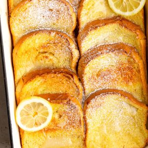 Baked iced lemon french toast with golden brioche, lemon glaze, and a light dusting of powdered sugar.