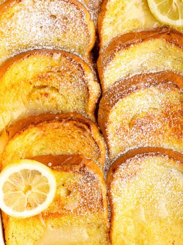 Baked iced lemon french toast with golden brioche, lemon glaze, and a light dusting of powdered sugar.