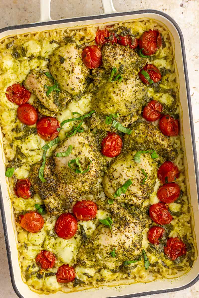Finished pesto chicken rice bake in a casserole dish topped with basil and melted mozzarella.