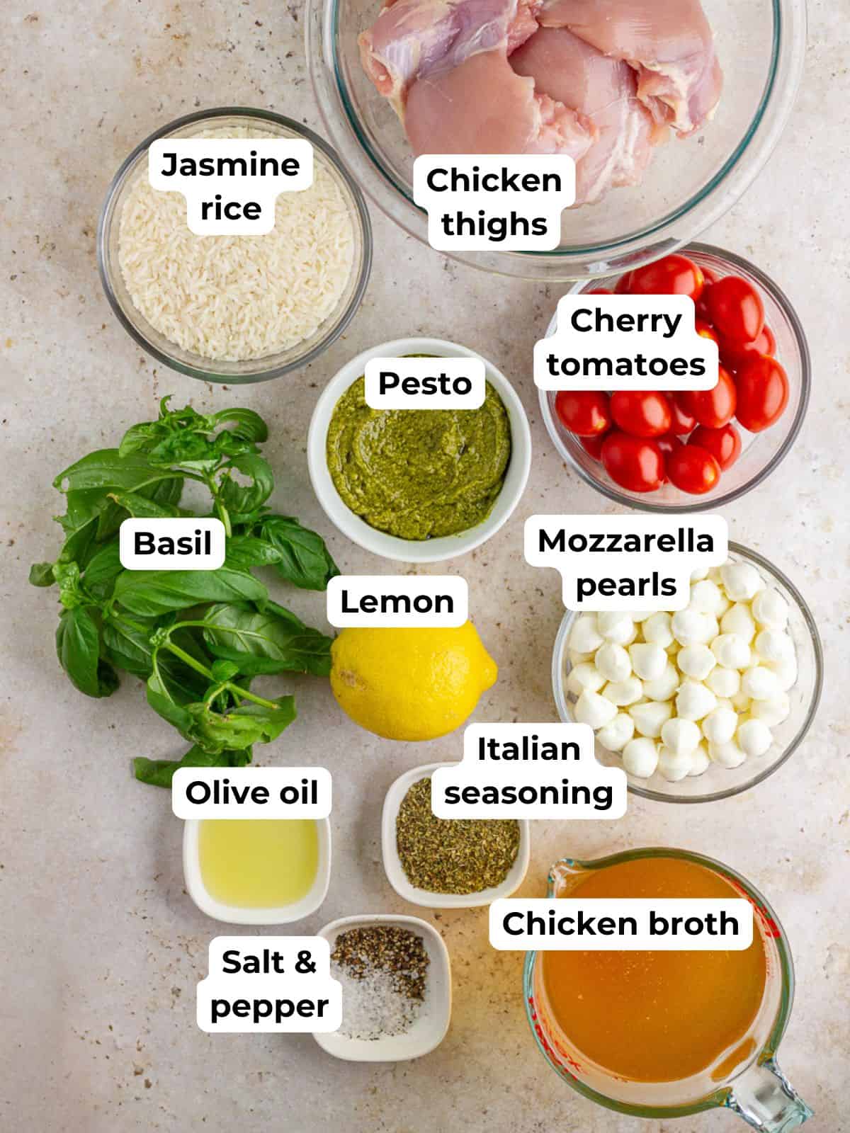 Ingredients for pesto chicken rice bake including jasmine rice, chicken thighs, pesto, tomatoes, mozzarella, and basil.