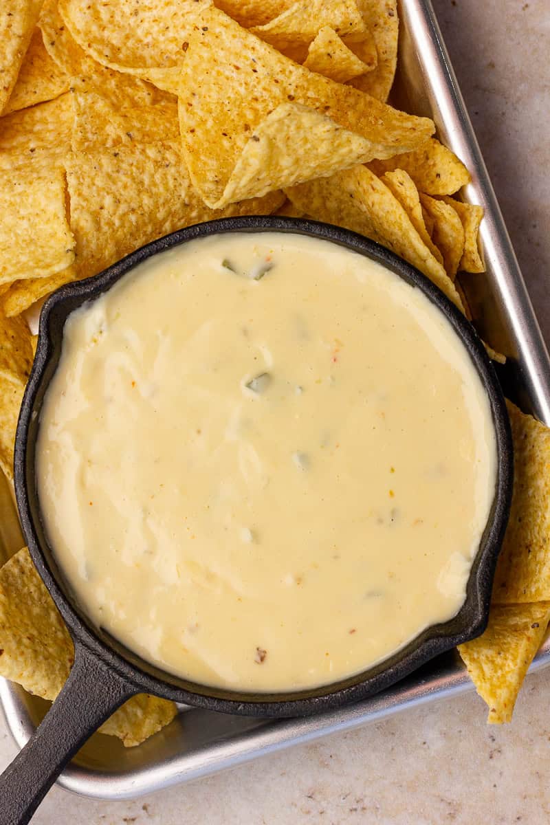 A skillet of creamy spicy queso served with tortilla chips on a tray.