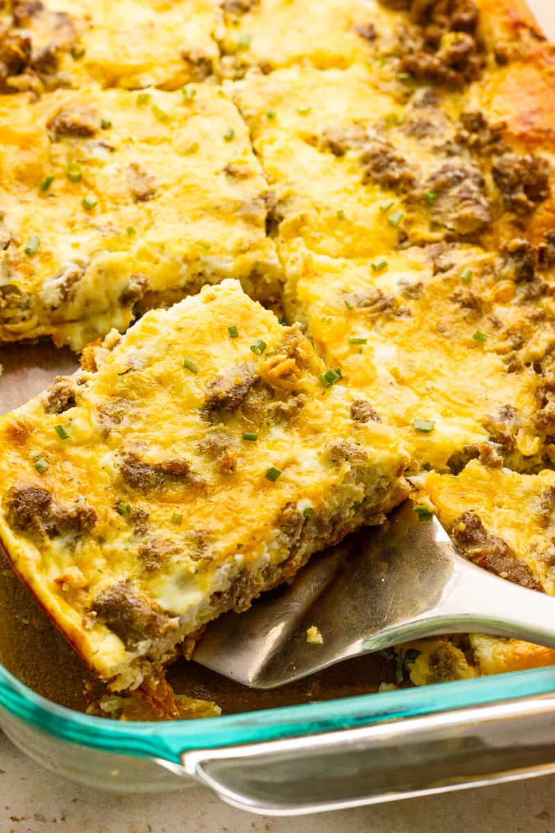 Close-up of a cheesy breakfast casserole slice with sausage and crescent roll base.
