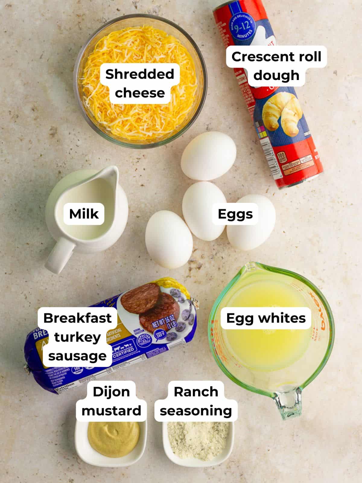 Ingredients for breakfast casserole with crescent rolls including eggs, egg whites, sausage, cheese, milk, and dough.