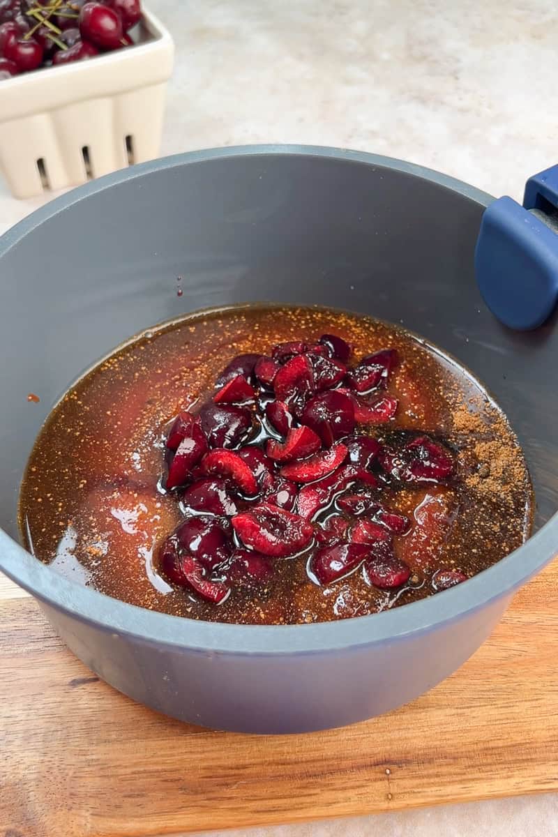 Fresh cherries and BBQ sauce ingredients are combined in a saucepan before simmering.