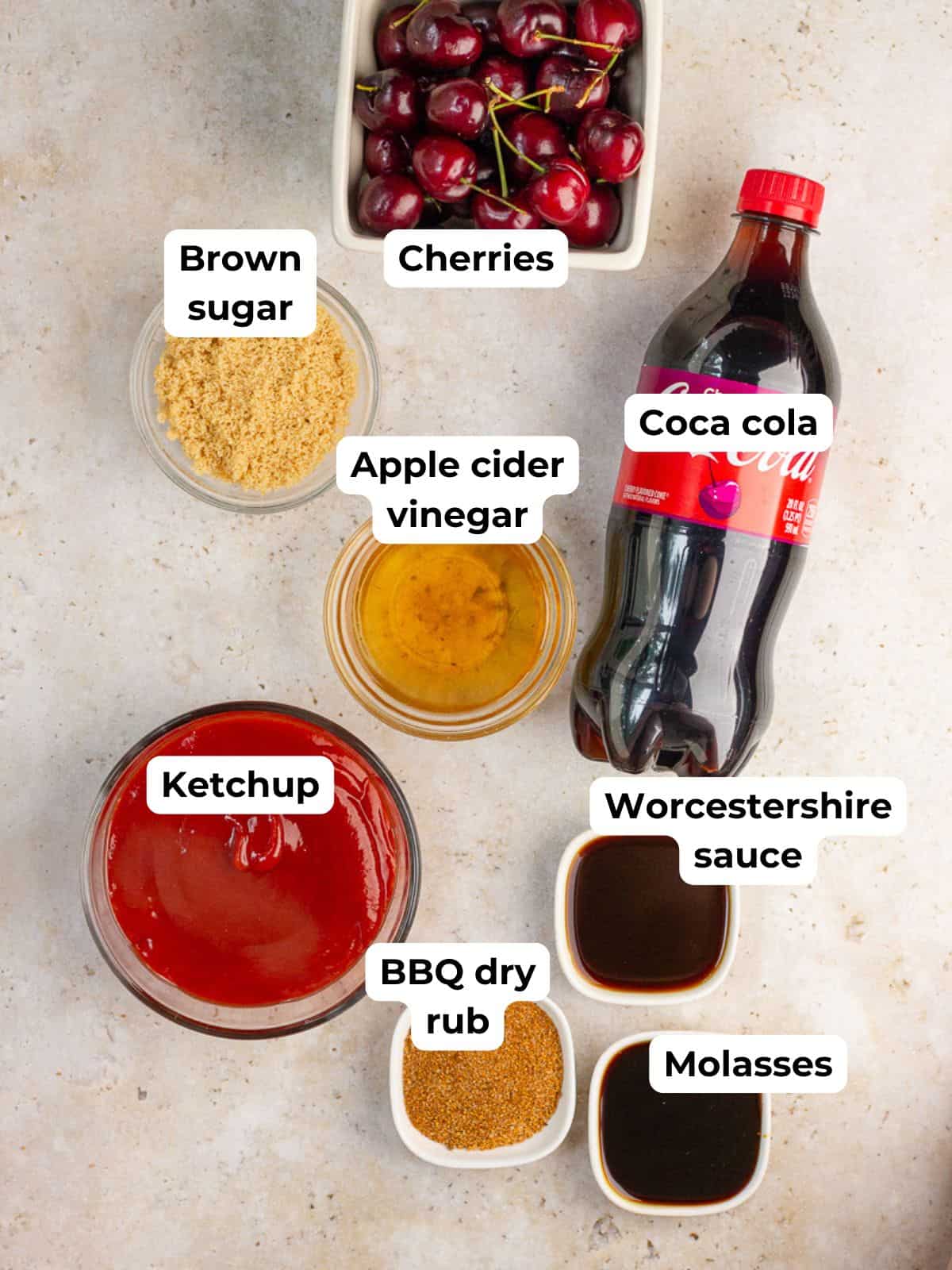 The ingredients for cherry cola BBQ sauce are arranged and labeled on a light countertop.