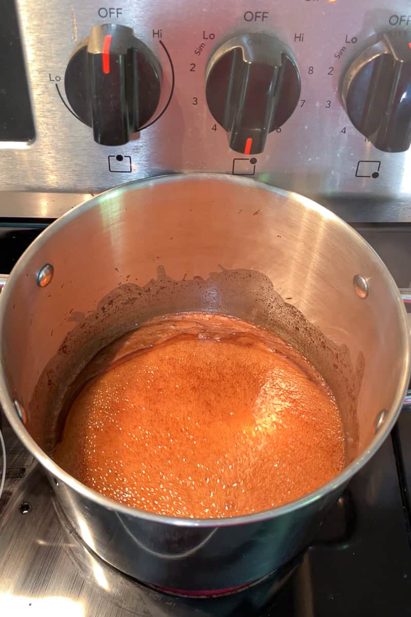 A cinnamon sugar mixture bubbles in a heavy pot on the stove.