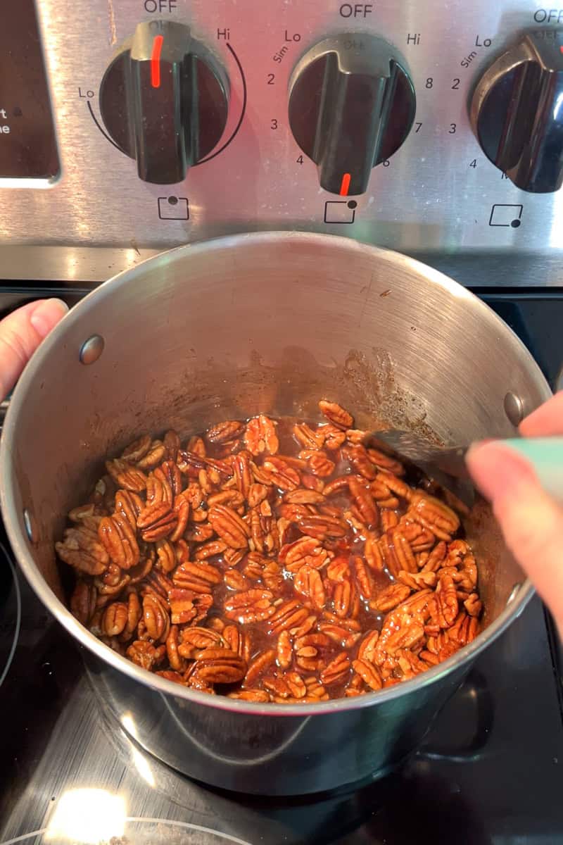 Pecan halves are stirred into the cinnamon sugar mixture on the stove.