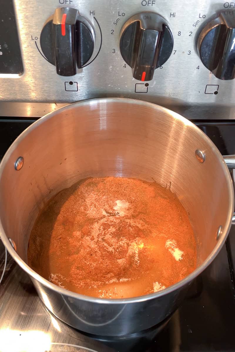 Cinnamon, sugar, salt, and water are combined in a pot before cooking.