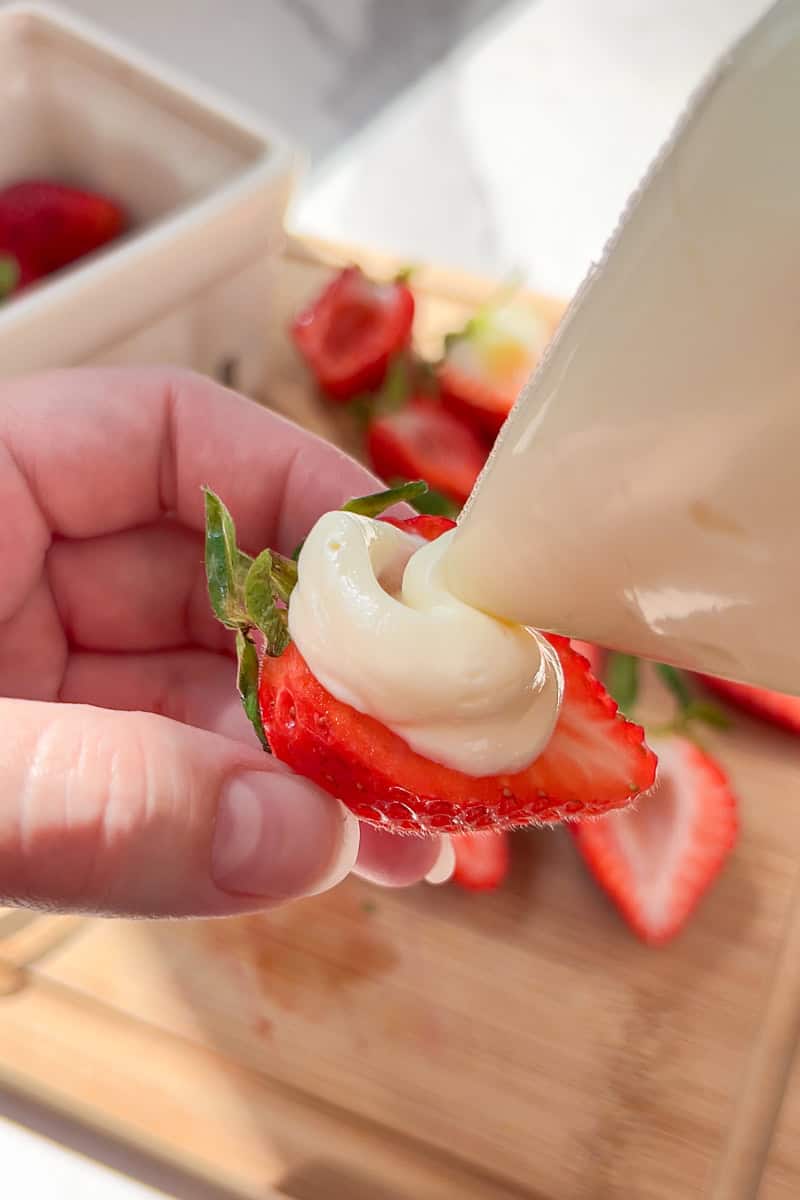 Cheesecake filling gets piped into a sliced strawberry for deviled strawberries.