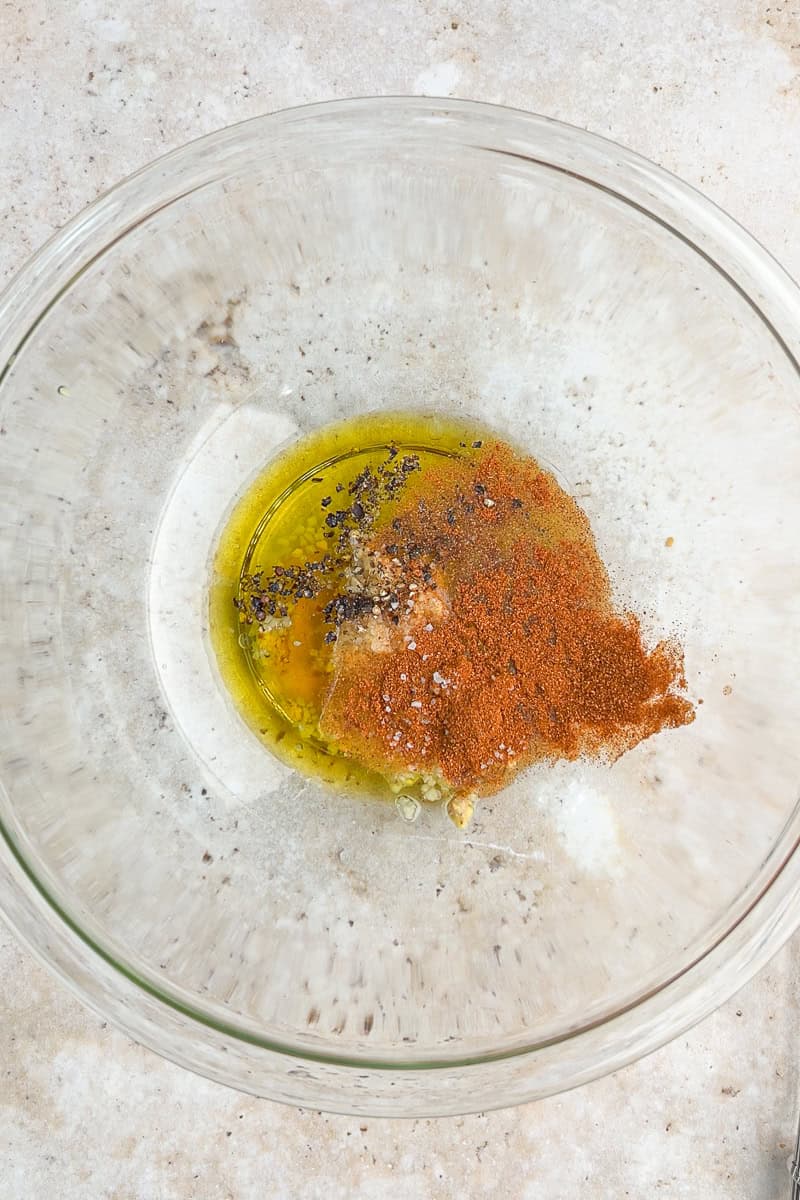 Honey mustard marinade ingredients are added to a glass mixing bowl.