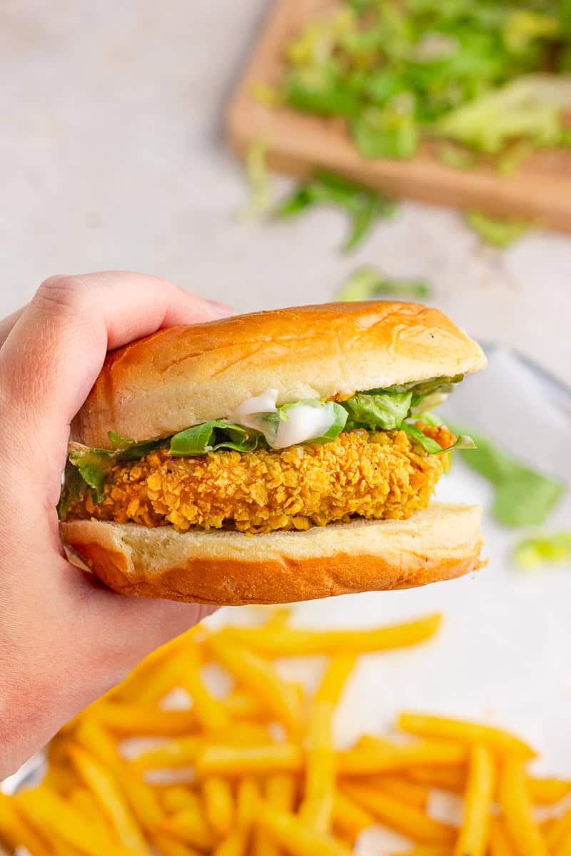Hand holding a crispy homemade McChicken sandwich on a brioche bun with lettuce and mayo.
