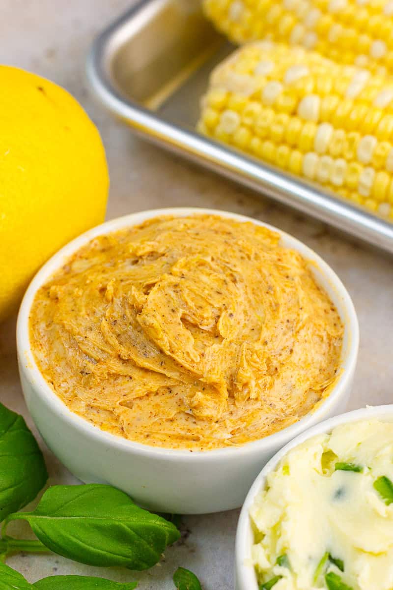A bowl of Old Bay butter is served with corn, lemon, basil, and another flavored butter.