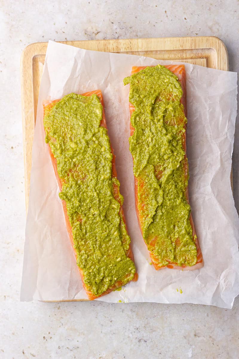 Salmon fillets are topped with a thin layer of pesto and ready for the next step.