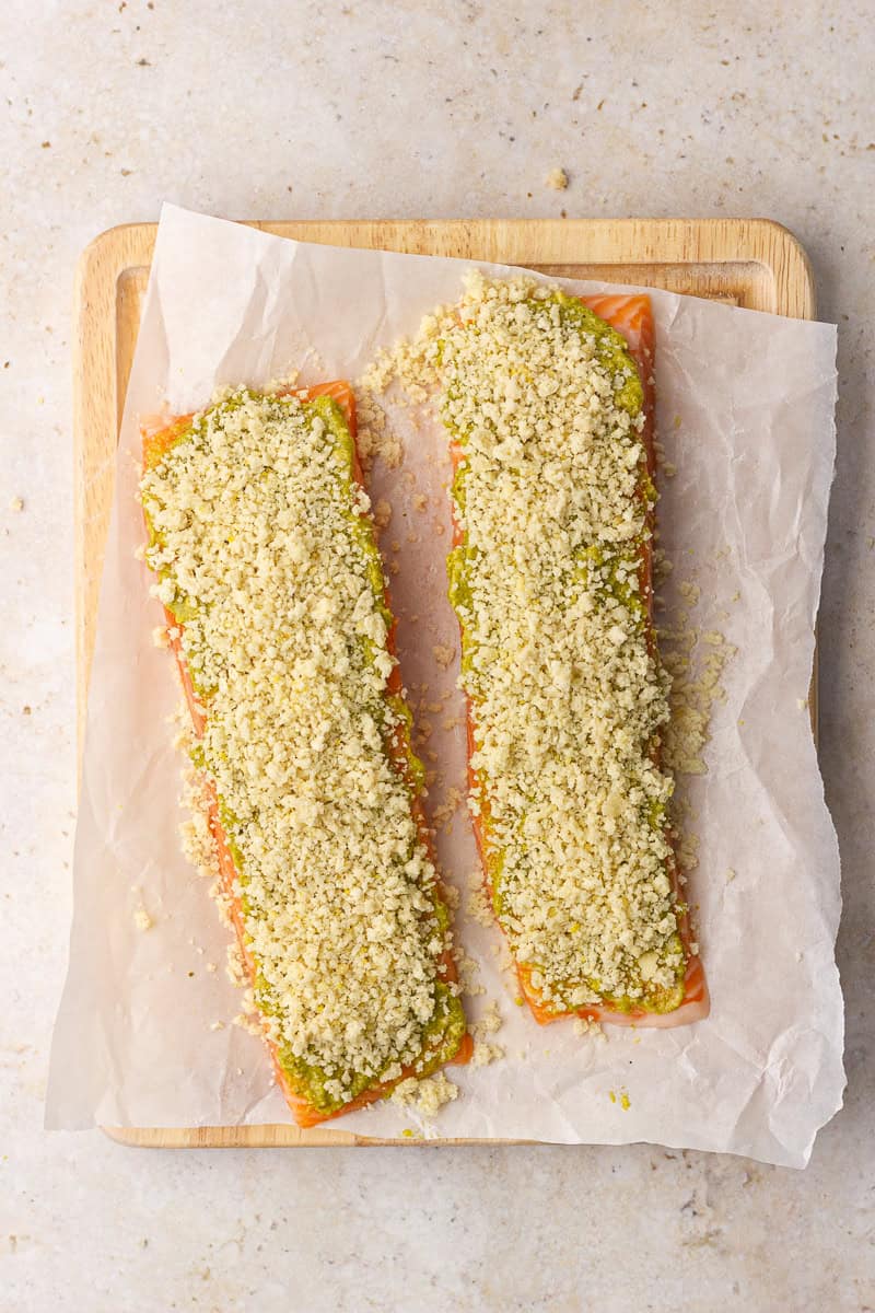 Salmon fillets are coated with pesto and topped with the panko parmesan mixture before cooking.