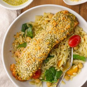 Crispy pesto crusted salmon is served over a bright and fresh orzo salad with lemon on the side.