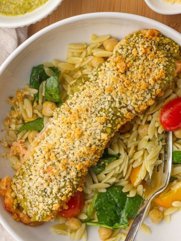 Crispy pesto crusted salmon is served over a bright and fresh orzo salad with lemon on the side.