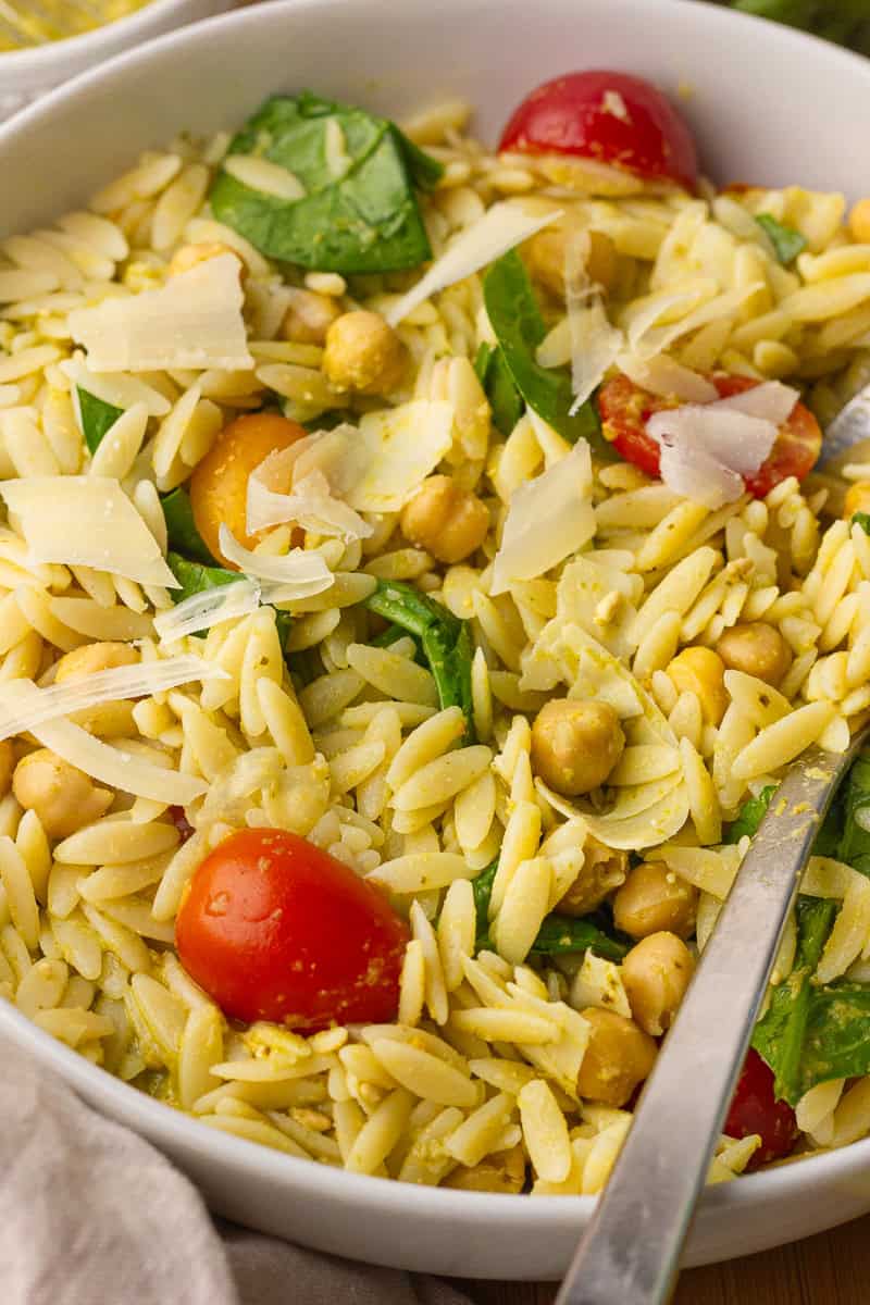 Close-up of pesto orzo salad showing tender orzo, chickpeas, parmesan, and fresh spinach.