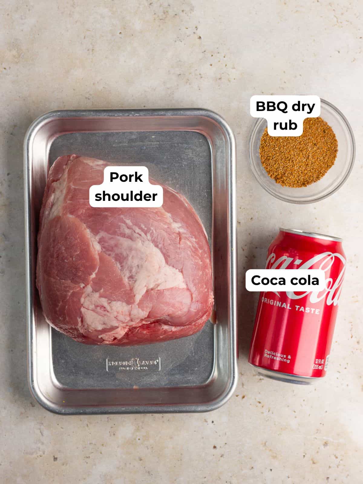 Pork shoulder, BBQ dry rub, and Coca-Cola are arranged for pulled pork with Coke.