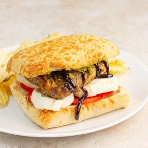 This chicken Caprese sandwich features grilled balsamic chicken, fresh mozzarella, tomato, pesto, and balsamic glaze on ciabatta bread.