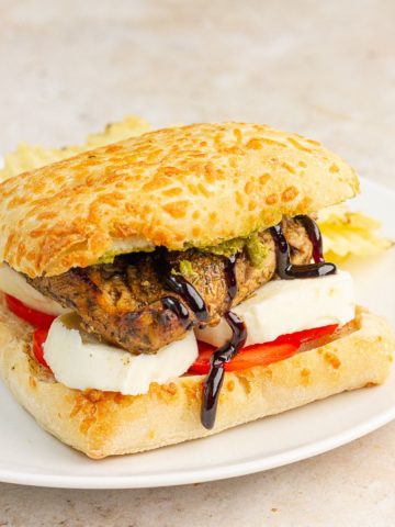 This chicken Caprese sandwich features grilled balsamic chicken, fresh mozzarella, tomato, pesto, and balsamic glaze on ciabatta bread.