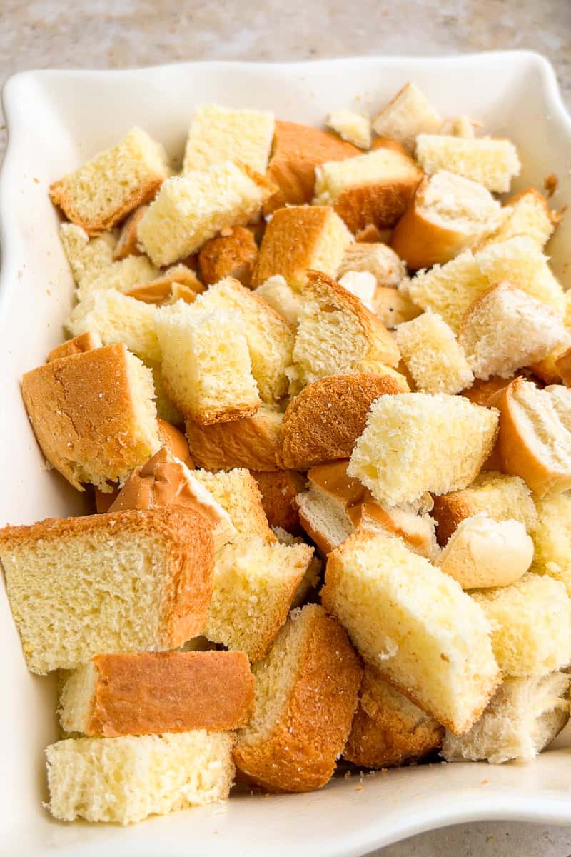 Cubed brioche bread fills a baking dish to prepare peach French toast casserole.
