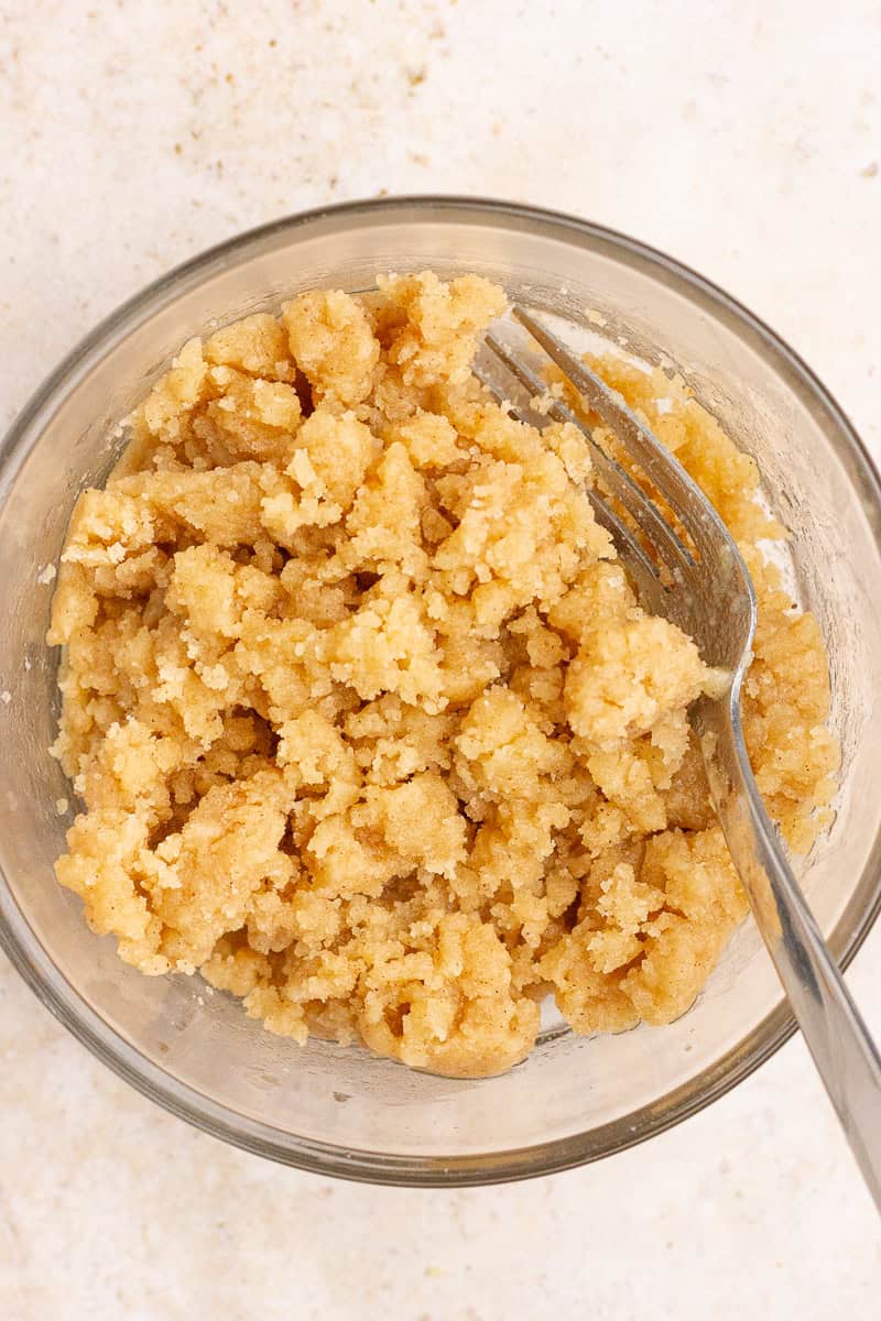 A bowl of cinnamon crumb topping is mixed together for peach cobbler French toast casserole.
