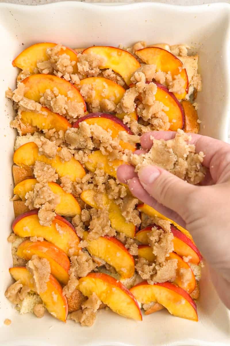 Crumb topping is sprinkled over fresh peach slices before baking the peach French toast casserole.