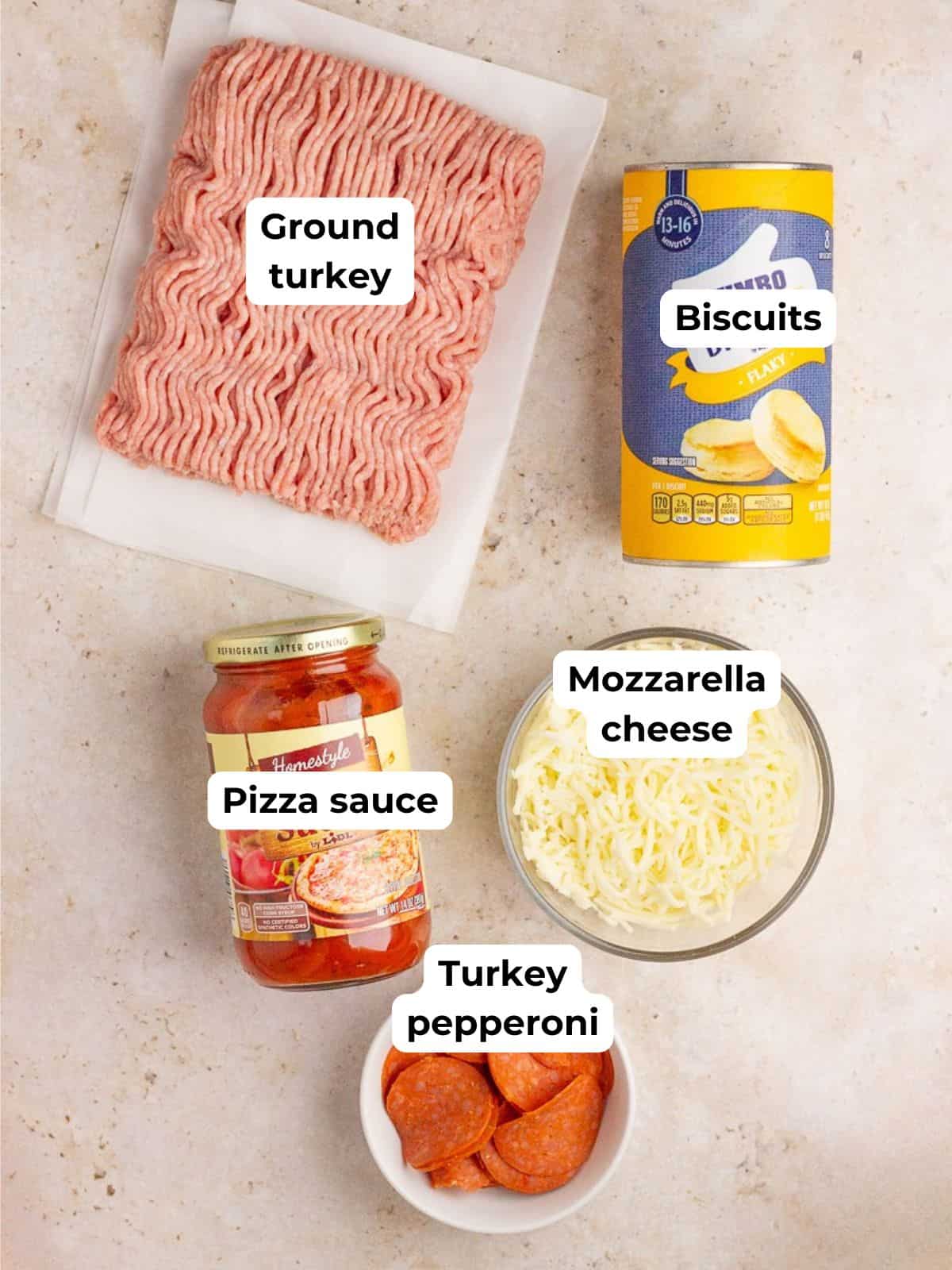 Ground turkey, biscuits, pizza sauce, mozzarella cheese, and turkey pepperoni are displayed as the ingredients for biscuit pizza casserole.