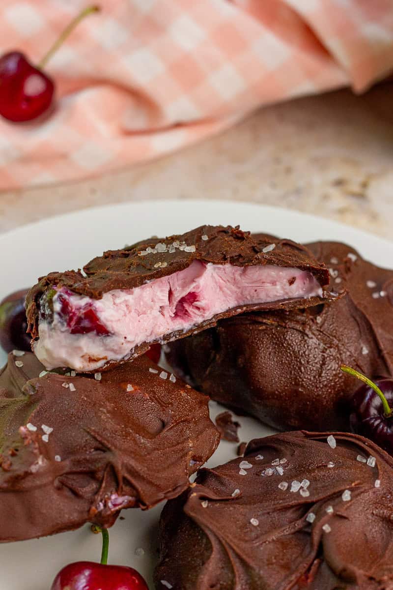 A chocolate covered frozen yogurt bite shows the creamy cherry yogurt filling inside.