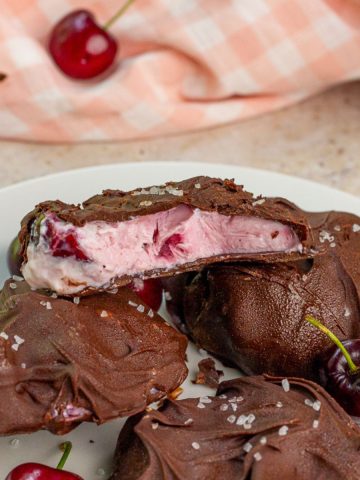 Chocolate covered cherry yogurt bites are topped with flaky salt on a plate.