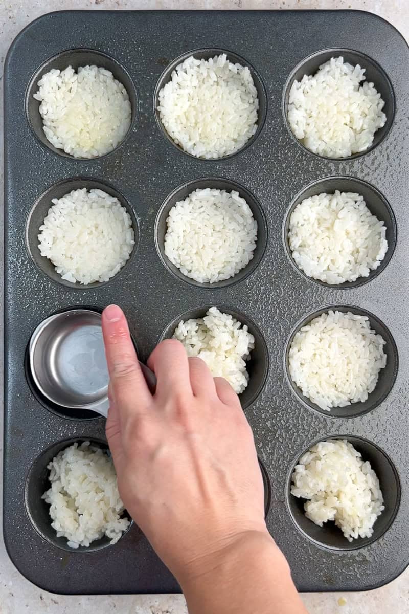 Cooked short-grain rice is pressed into a greased muffin tin to form rice cups.