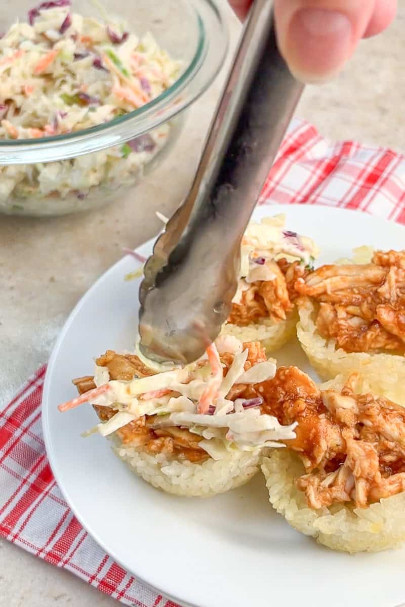 Ranch coleslaw is spooned onto BBQ chicken crispy rice cups before serving.