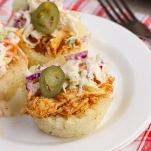 BBQ chicken crispy rice cup topped with ranch coleslaw and pickled jalapeños on a white plate.