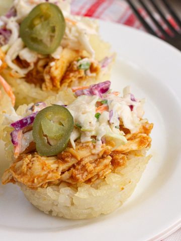 BBQ chicken crispy rice cup topped with ranch coleslaw and pickled jalapeños on a white plate.