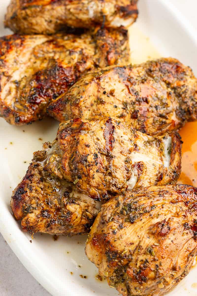 A close-up of juicy grilled balsamic chicken shows caramelized grill marks and herby marinade.