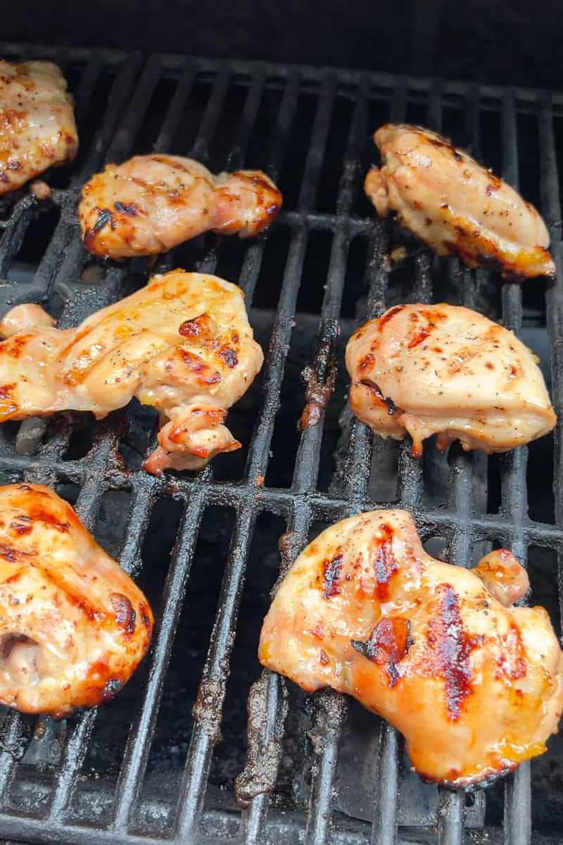 Peach glazed chicken thighs cook on the grill until lightly charred.