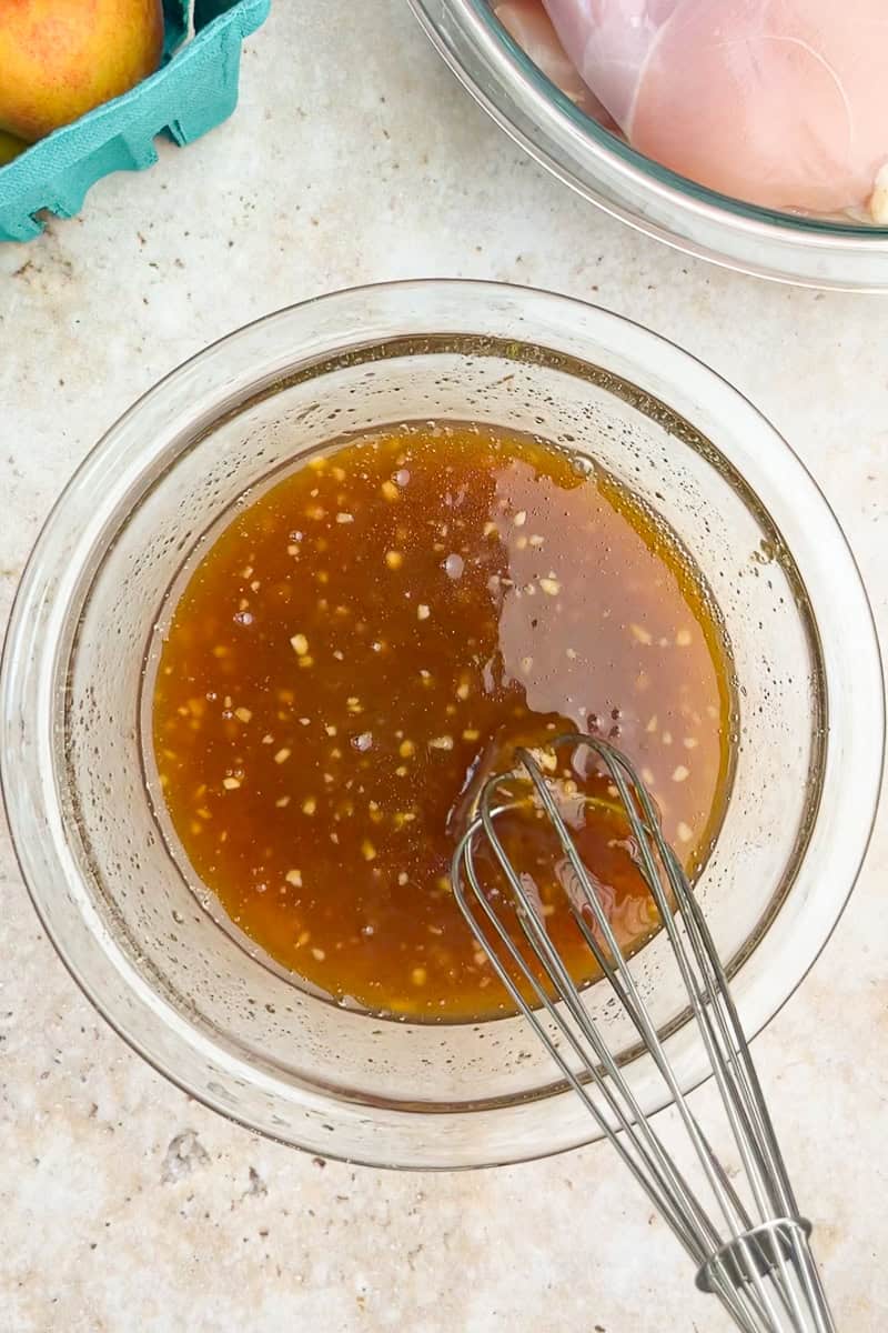 A sweet peach marinade is whisked together in a glass bowl.