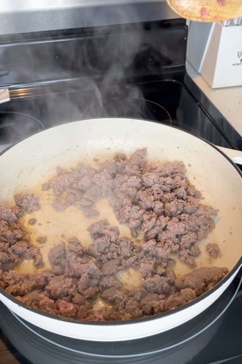 Turkey breakfast sausage cooks in a skillet before adding the vegetables and tomato sauce.