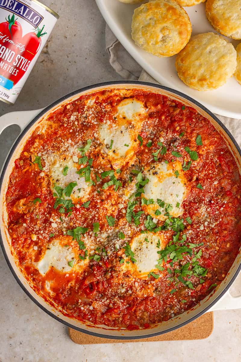 A skillet of Southern-style high protein shakshuka is topped with parsley and cheese and served with biscuits.