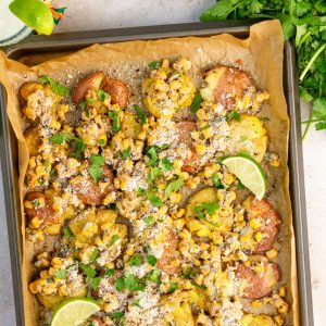 Mexican street corn smashed potatoes are topped with cotija cheese, cilantro, lime, and creamy corn topping.