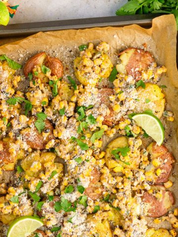Mexican street corn smashed potatoes are topped with cotija cheese, cilantro, lime, and creamy corn topping.