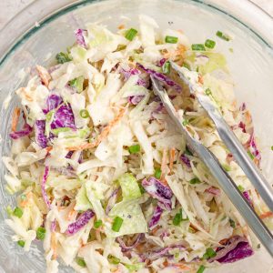 Creamy ranch coleslaw with purple cabbage, carrots, and green onions is served in a bowl.