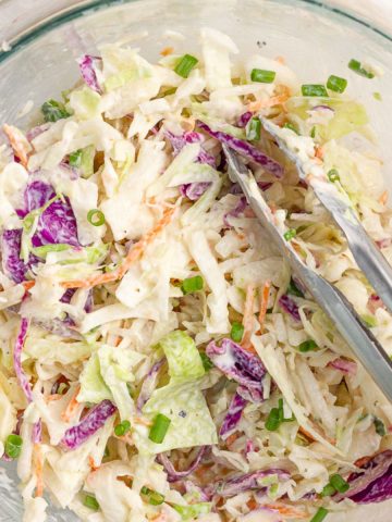 Creamy ranch coleslaw with purple cabbage, carrots, and green onions is served in a bowl.
