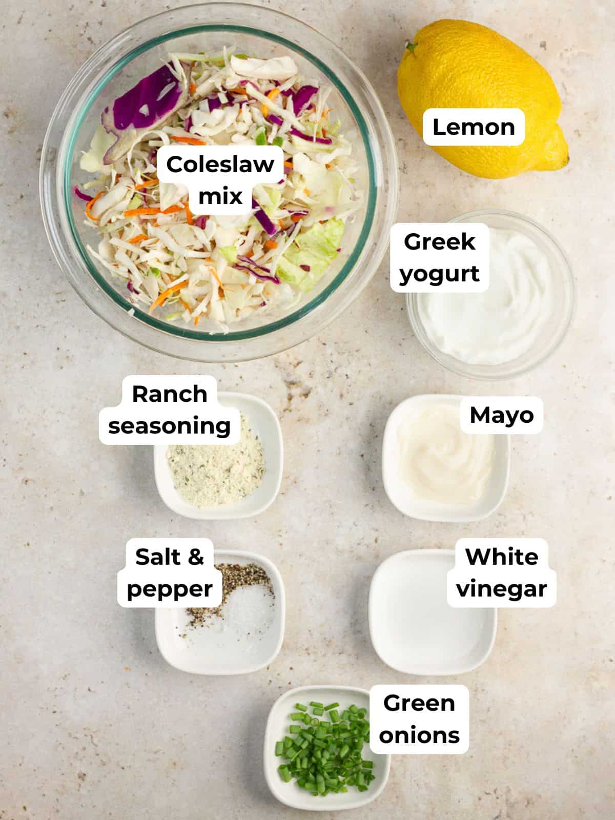 Ingredients for ranch coleslaw are labeled on a countertop before mixing.